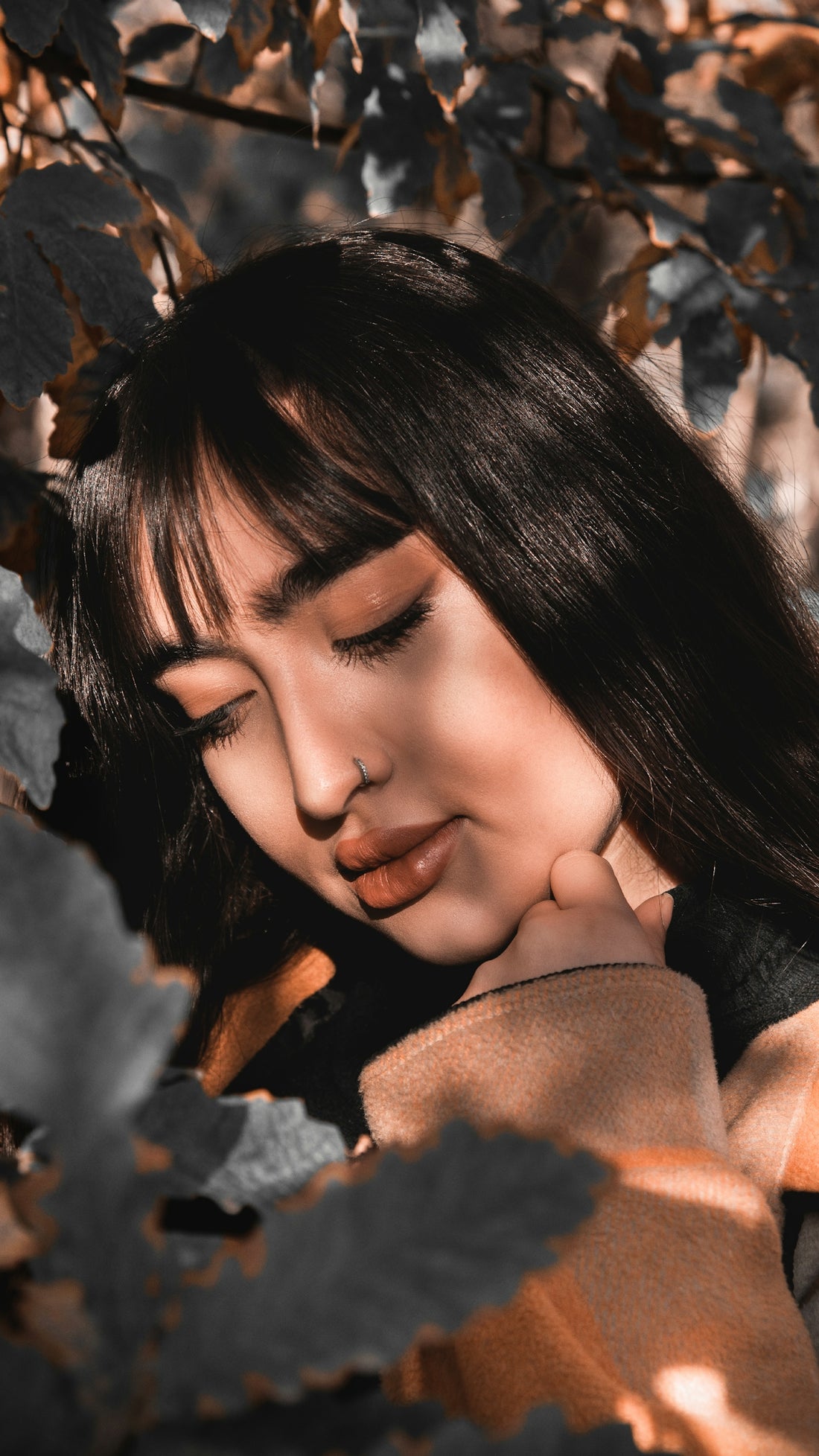 Woman with eyes closed amongst autumn leaves
