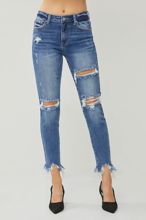 Blue distressed skinny jeans with ripped knees and frayed hems, styled with black heels.