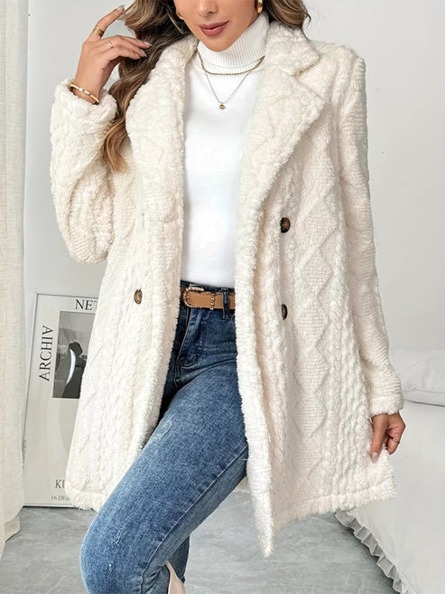 Cream faux-sherpa long coat with a textured pattern and double-breasted buttons, worn over a white turtleneck and jeans.